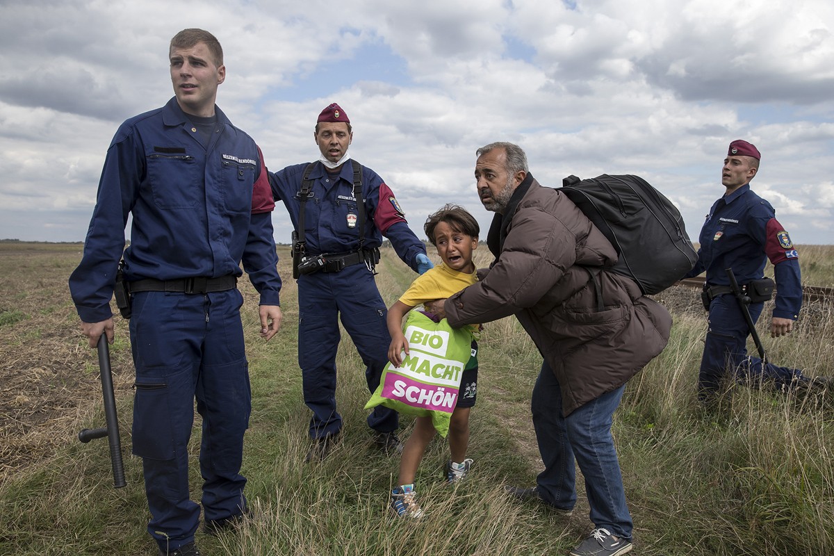 Ngày 8/9/2015, các cảnh sát Hungary ngăn cản cha con người tị nạn Syria Osama Abdul Mohsen và con trai Zaid khi họ đang cố gắng chạy trốn giới chức trách sở tại ở làng Roszke, Hungary.